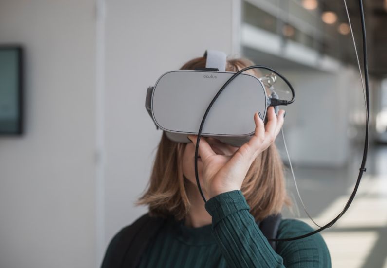Innovations - woman in black sweater holding white and black vr goggles