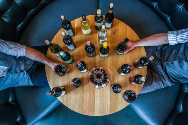 Tasting Session - person holding glass bottle on round brown wooden table
