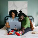 Technology - a woman sitting on a bed using a laptop