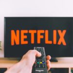 Subscriptions - person holding remote pointing at TV