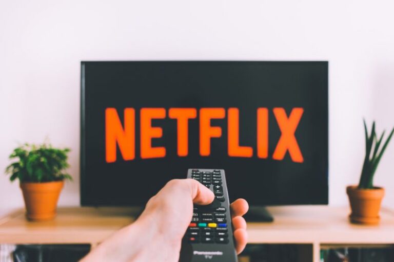 Subscriptions - person holding remote pointing at TV
