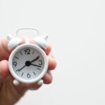 Extraction Time - person holding white mini bell alarmclock