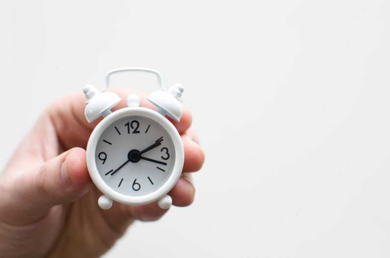 Extraction Time - person holding white mini bell alarmclock