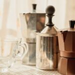 Milk Frother - stainless steel teapot beside clear glass mug