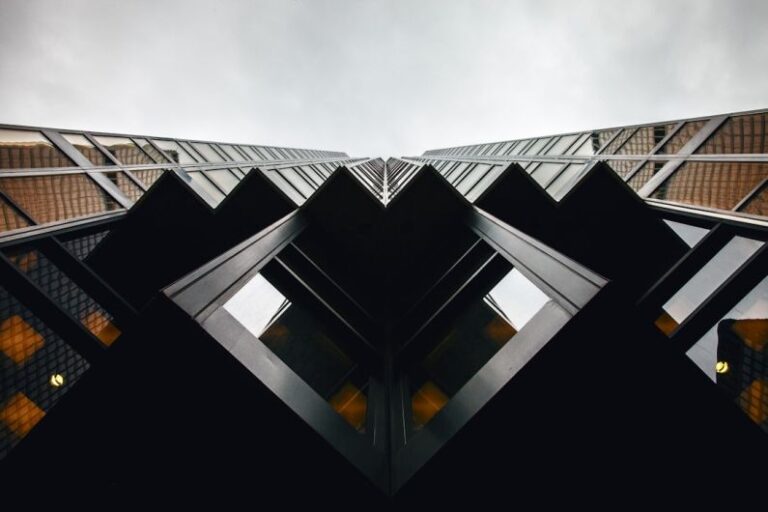 Symmetry - lowangle photography of brown and black high-rise building under cloudy sky