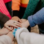Community - person in red sweater holding babys hand