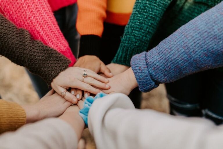 Community - person in red sweater holding babys hand