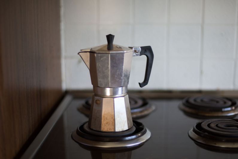 Percolator - gray moka pot on electric coil stove selective focus photo