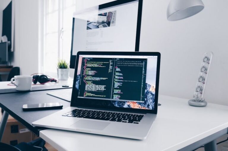 Equipment Maintenance - A MacBook with lines of code on its screen on a busy desk